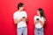 Internet addicted. Two young lovers are busy at their mobile phones in social nets isolated on red background