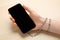 Internet addiction. Closeup view of woman holding smartphone at wooden table, hand chained to device