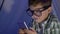 Internet child in eyeglasses watches video into mobile phone in wigwam close-up