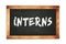 INTERNS text written on wooden frame school blackboard