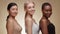 Interracial beauty. Profile portrait of mixed ladies turning faces to camera and smiling, posing over beige background