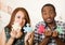 Interracial charming couple holding up large puzzle pieces and happily interacting having fun, blurry studio background