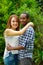 Interracial charming couple wearing casual clothes embracing and posing for camera in outdoors environment