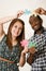 Interracial charming couple wearing casual clothes holding up large puzzle pieces and interacting happily, white studio