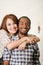 Interracial charming couple wearing casual clothes posing embracing friendly and smiling, white studio background