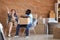 Interracial couple with boxes resting on chairs indoors. Moving into new house