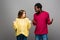 Interracial couple in knitted sweaters looking at each other on grey background