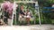 Interracial couple sitting, eating popsicle on a swinging bench in natural park.