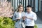 Interracial partnership. Business woman and Asian business man standing near office with tablet