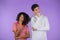 Interracial thinking pondering couple on purple studio background. Man and woman look in different directions and