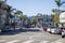 An intersection at Cahuenga Boulevard and Yucca street with apartments, shops, lush green palm trees, cars parked and driving