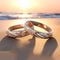 Intertwined Wedding Rings with Diamonds and Pearls on a Sun-Kissed Beach at Sunset