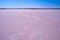 Intricate windblown salt patterns on pink lake.