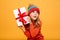 Intrigued Young girl in sweater and hat holding gift box