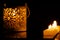 Intrincate metal candle holder with a lighting scented candle are displayed on the blak stone table in the dark living room of the