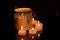 Intrincate metal candle holder with a lighting scented candle are displayed on the blak stone table in the dark living room of the