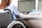 Invalid or disabled woman sitting wheelchair working office desk computer