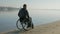 Invalid on wheel chair rides sand, cripple in wheelchair near river,