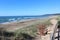 Inverness beach in Nova Scotia on a warm windy spring day with light surf crashing onto the sand.