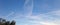 Inversion trail from an airplane in a blue sky, white streak of clouds