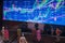 Investment graphics on screen with miniature people watching