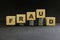 Investment scam, fraud and Ponzi scheme concept. Stack of coins on wooden blocks with word fraudulent in dark black background.