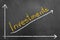 Investments chalk text and arrow up graphic on blackboard