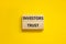 Investors trust symbol. Concept words Investors trust on wooden blocks on a beautiful yellow table yellow background. Business