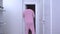 Invisible man in pink pajamas walks down the hallway of apartment into dark room. Special effects for shooting science