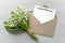 Invitation in a craft envelope with a spring bouquet of lilies of the valley, fresh flowers