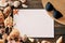 Invitation or greeting card mockup with straw hat, sunglasses and various seashells on dark wooden background,