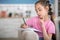 Involved dark-haired girl sitting on sofa, writing in her notebook