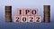 IPO 2022 - acronym on wooden cubes on a light background with coins