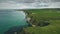 Ireland medieval castle ruins aerial view: rocky shore, wide valleys, fields, green landscape