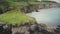 Ireland ocean coastal island aerial view: people hiking rope bridge Carrick-a-Rede at green cliff