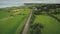 Ireland rural road aerial view: car driving up farmland. Irish green grass meadow, fields