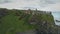 Ireland`s medieval castle ruins aerial view: cliffy shore of ocean gulf under cumulus grey clouds