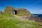 Irish landscape, green grass covered sea coast, with stone hill and cave, next to Ballintoy