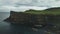 Irish ocean landscape: castle aerial shot. Epic ancient ruins on shore basalt cliff, green meadows