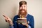 Irish redhead man with beard holding birthday cake with burning candles over isolated background very happy pointing with hand and