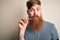 Irish redhead man with beard holding dental invisible aligner for tooth correction with a confident expression on smart face