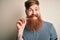 Irish redhead man with beard holding dental invisible aligner for tooth correction with a happy face standing and smiling with a