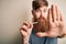 Irish redhead man with beard holding dental invisible aligner for tooth correction with open hand doing stop sign with serious and