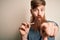 Irish redhead man with beard holding dental invisible aligner for tooth correction pointing with finger to the camera and to you,