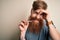 Irish redhead man with beard holding dental invisible aligner for tooth correction stressed with hand on head, shocked with shame