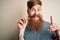 Irish redhead man with beard holding dental invisible aligner for tooth correction surprised with an idea or question pointing