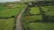 Irish rural road aerial view: green meadows, cottages and hillside farmlands. Picturesque landscape