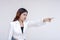 An irked and irritable young woman glaring and pointing to the right. Isolated on a white background