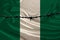 Iron barbed wire against the background of the national silk flag of the state of Nigeria, concept of imprisonment for offenders,