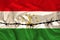 Iron barbed wire against the background of the national silk flag of the state of Tajikistan, the concept of imprisonment for